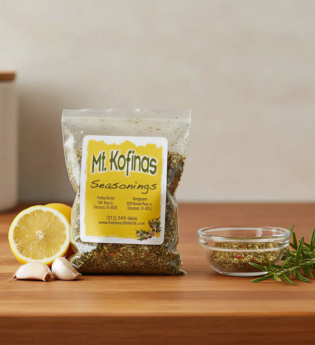 Pouch of Mt. Kofinas Seasonings on a board with lemon, garlic, rosemary and a bowl of spice