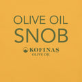 Close-up of a yellow-gold t-shirt printed with 'Olive Oil Snob' and the Kofinas logo