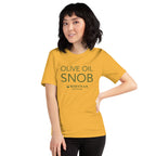 Person wearing a yellow-gold Olive Oil Snob t-shirt with a hand on their hip